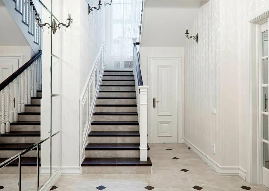 这所房子拥有一个楼梯，深棕色的地板和白色的栏杆，由优雅的壁灯照亮。