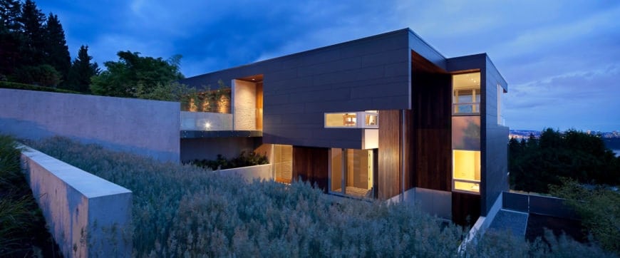 精致的房子覆盖着绿色，以混凝土和木材结合以及玻璃窗为特色。