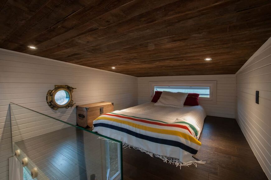 宽敞的白墙阁楼卧室配有深色木天花板和地板
