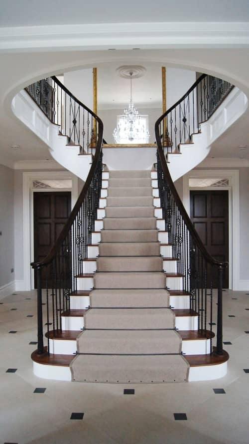 传统的楼梯以华丽的铁主轴和深色木扶手为特色。它有木制的踏板和白色的立管，上面铺着灰色的地毯。