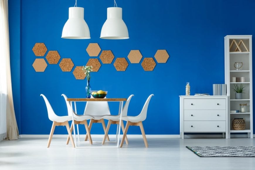 一个设计干净的餐厅，蓝色的墙壁，白色的椅子，白色的吊灯，八角形的墙壁。