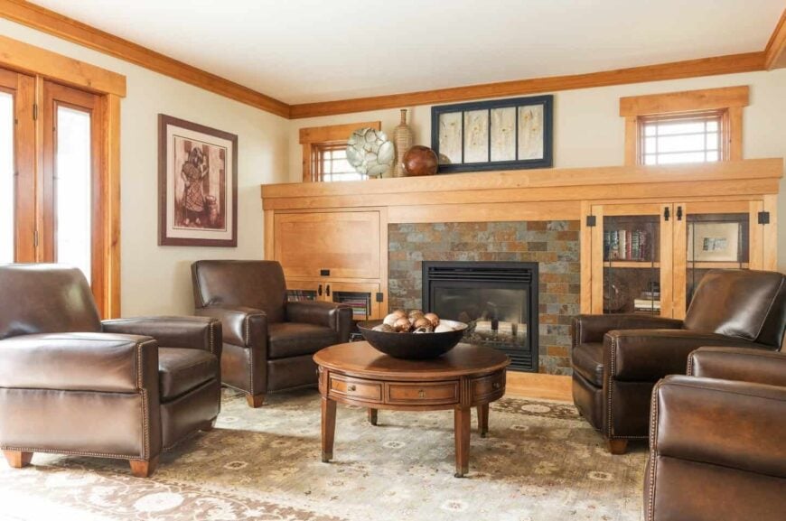 在这间小客厅里，正对着壁炉的木桌周围环绕着棕色皮椅。整个区域都铺着绿色的复古地毯。
