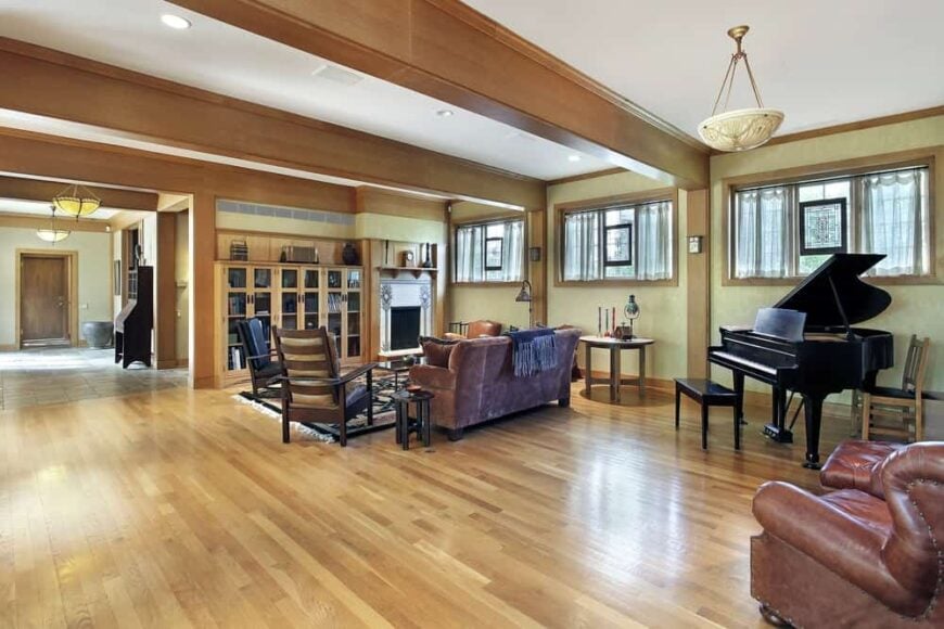 宽敞的客厅，一张棕色沙发，真皮躺椅和一架小型三角钢琴放在硬木地板上。