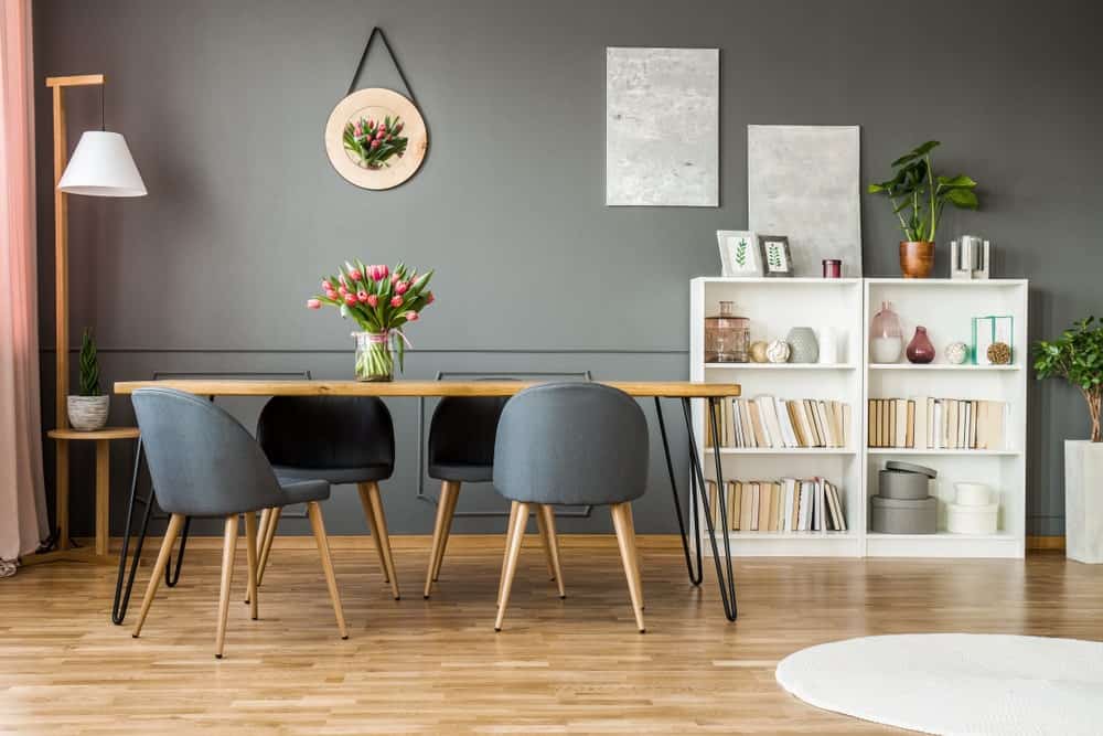 这间餐厅以木制餐桌搭配现代椅子和白色书架为特色。一对灰色帆布和郁金香墙壁装饰安装在灰色墙壁上。