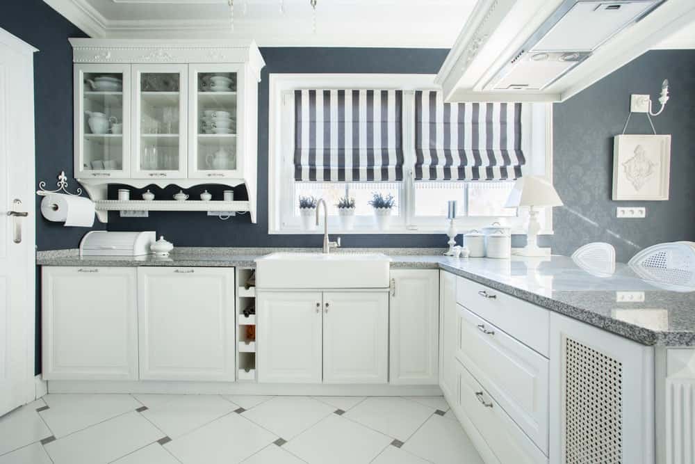 这间厨房拥有深灰色的墙壁和时尚的白色瓷砖地板。厨房的柜台和橱柜看起来也很完美。