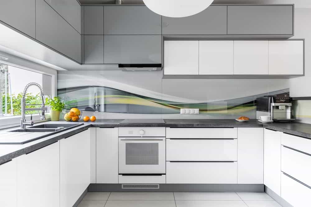 现代厨房设有白色厨房柜台和灰色台面。厨房的墙壁看起来非常吸引人。