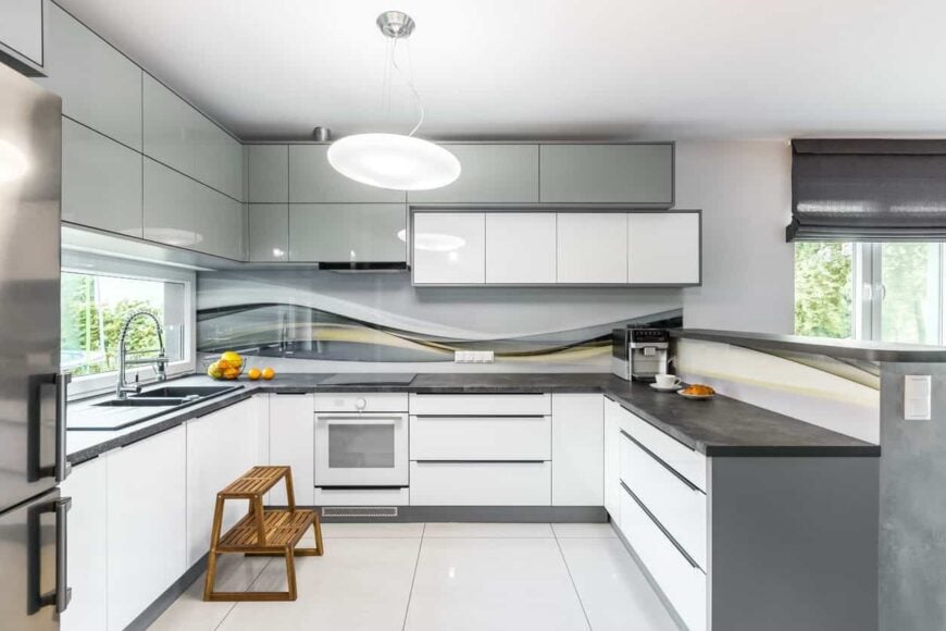 现代厨房以白色瓷砖地板和灰色橱柜为特色，并配有时尚的深灰色台面。