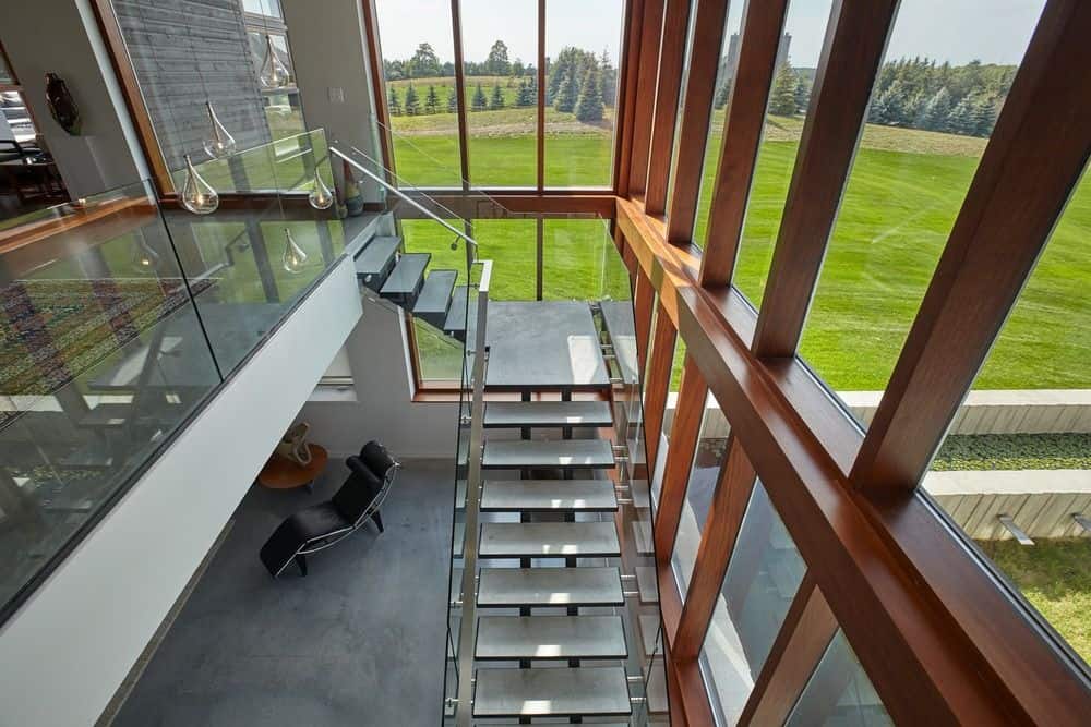 带有开放式立管和玻璃栏杆的现代楼梯与落地窗相辅相成，可以俯瞰可爱的户外风景。