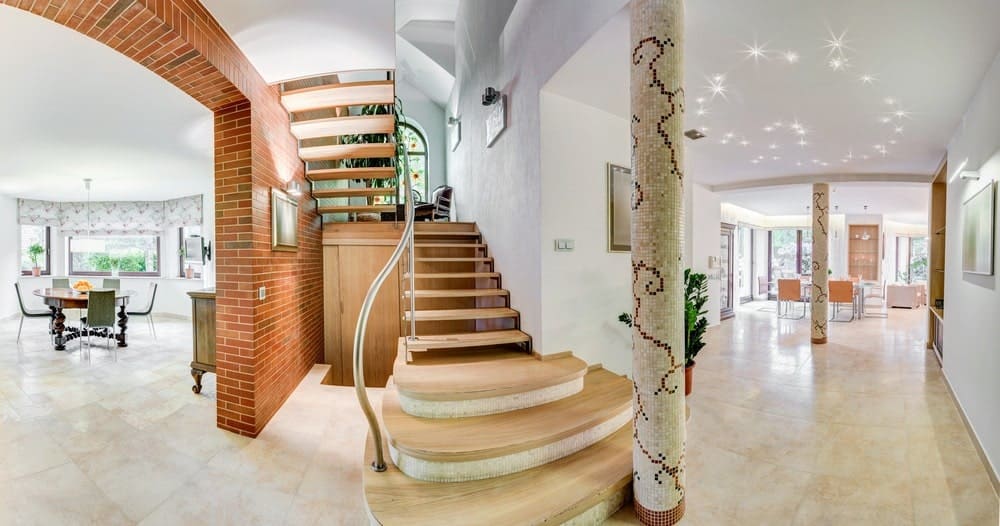 可爱的木质半旋转楼梯，带钢扶手和白色和砖墙的开放式立管。通过放置储物柜，空间最大化。