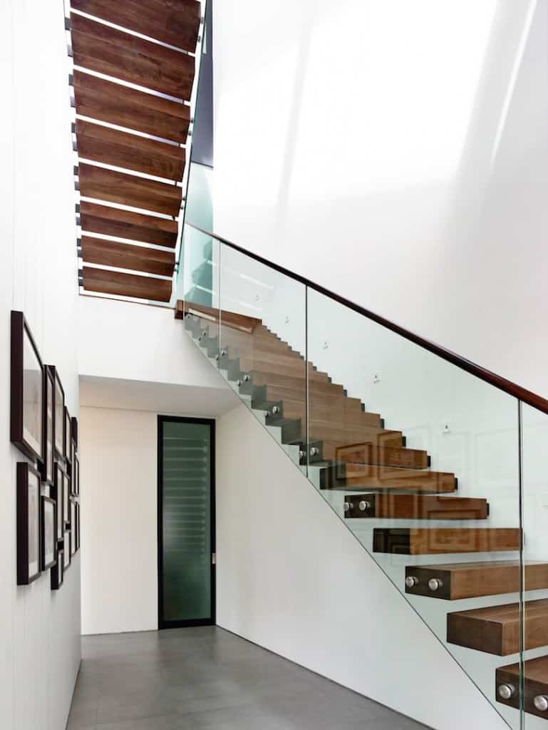 高的半旋转楼梯，木质扶手和玻璃栏杆沿着白墙。
