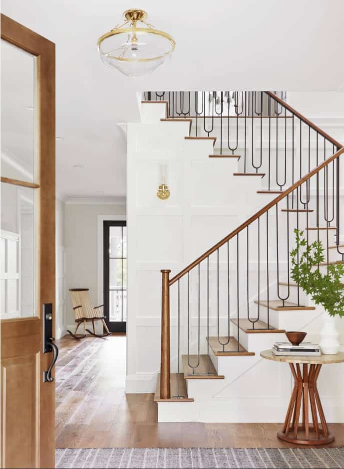 过渡的半旋转楼梯以锻铁华丽的纺锤和白色护壁板上的木踏板为特色，由金色壁灯和配套的枝形吊灯照明。