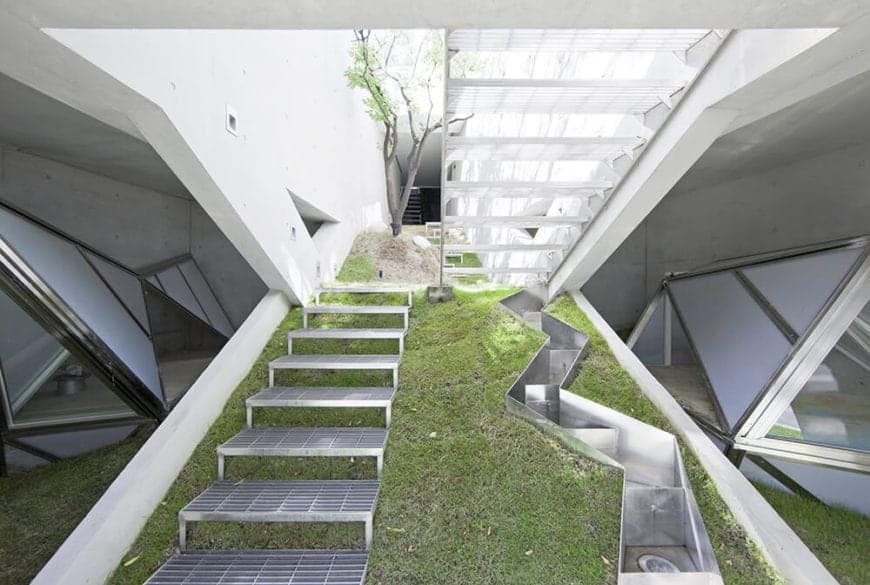 一个带有金属楼梯的斜坡和侧面的锯齿形照明箱，创造了一个光滑的现代几何设计。