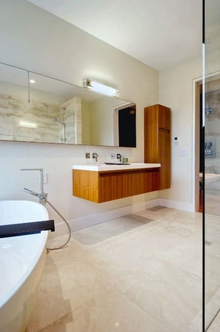 这间主浴室拥有一个浮动的梳妆台和一个巨大的白色独立式浴缸，以及一个步入式淋浴间。