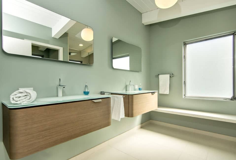 主浴室设有靠近窗户的长凳和几个由绿色墙壁环绕的浮动洗手池。