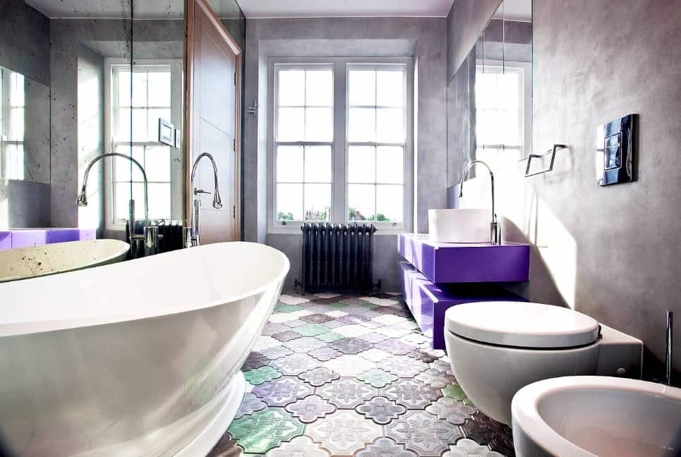 这间主浴室提供非常时尚的地板和漂亮的灰色墙壁，以及一个迷人的紫色浮动梳妆台和一个大型独立浴缸。