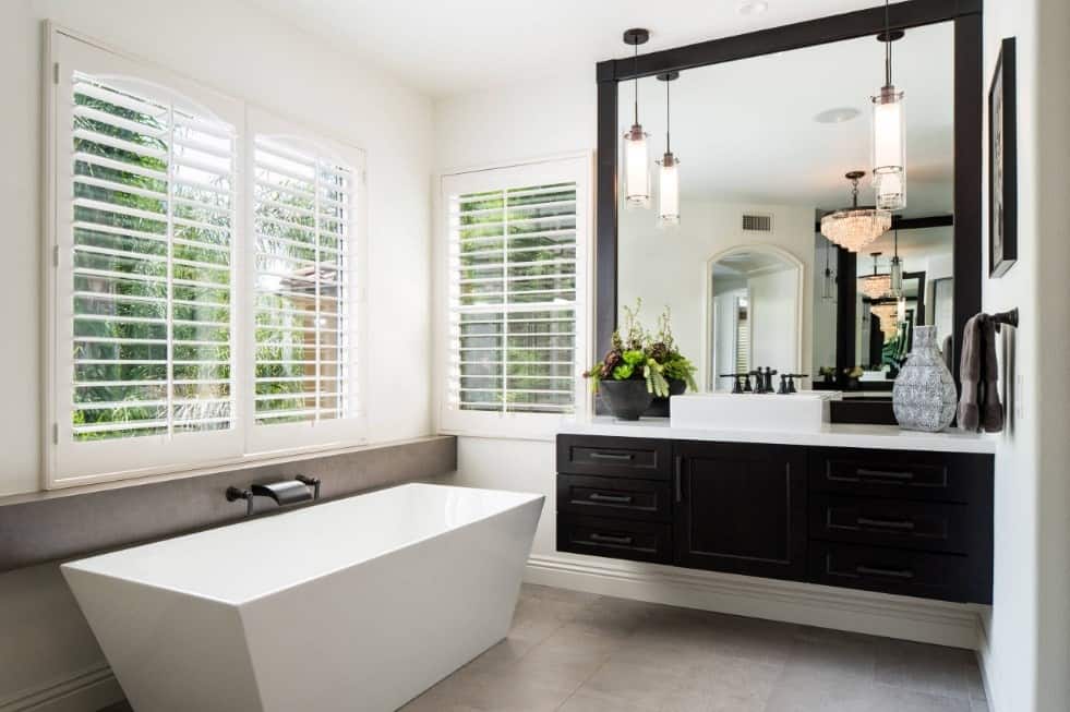 主浴室设有一个白色的独立浴缸，设置在灰色瓷砖地板上，以及一个带有容器水槽的浓缩咖啡装饰的浮动梳妆台。
