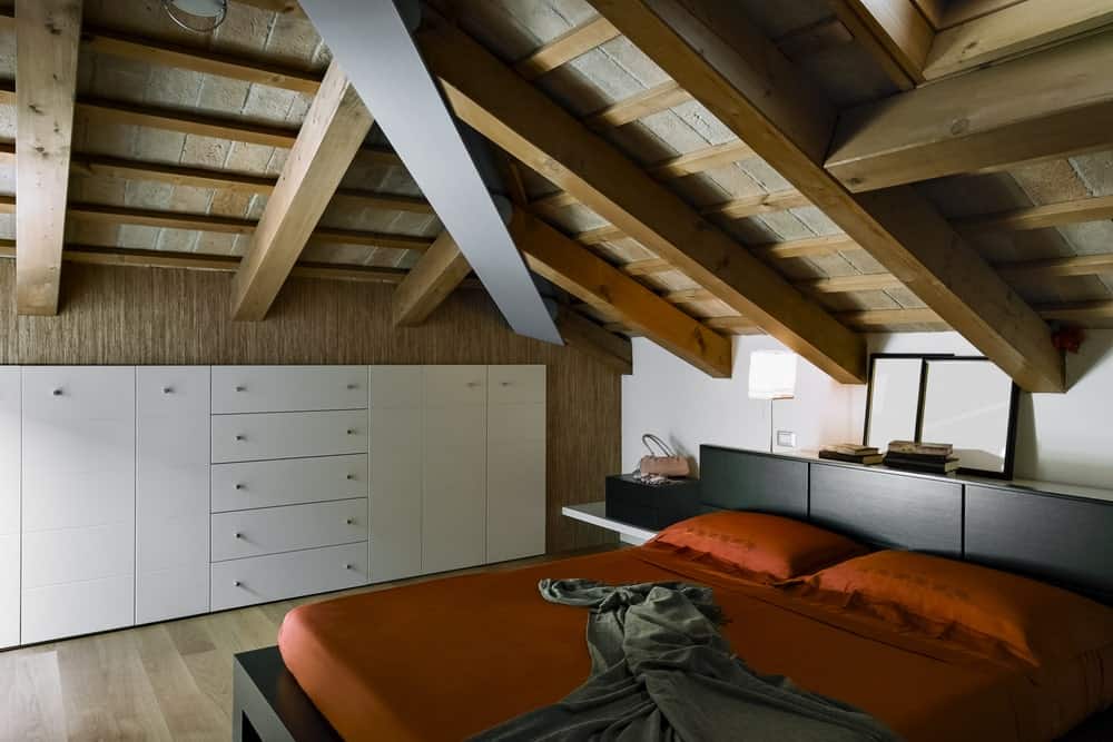 主卧室设有木制天花板下的时尚床设置，带有裸露的横梁。