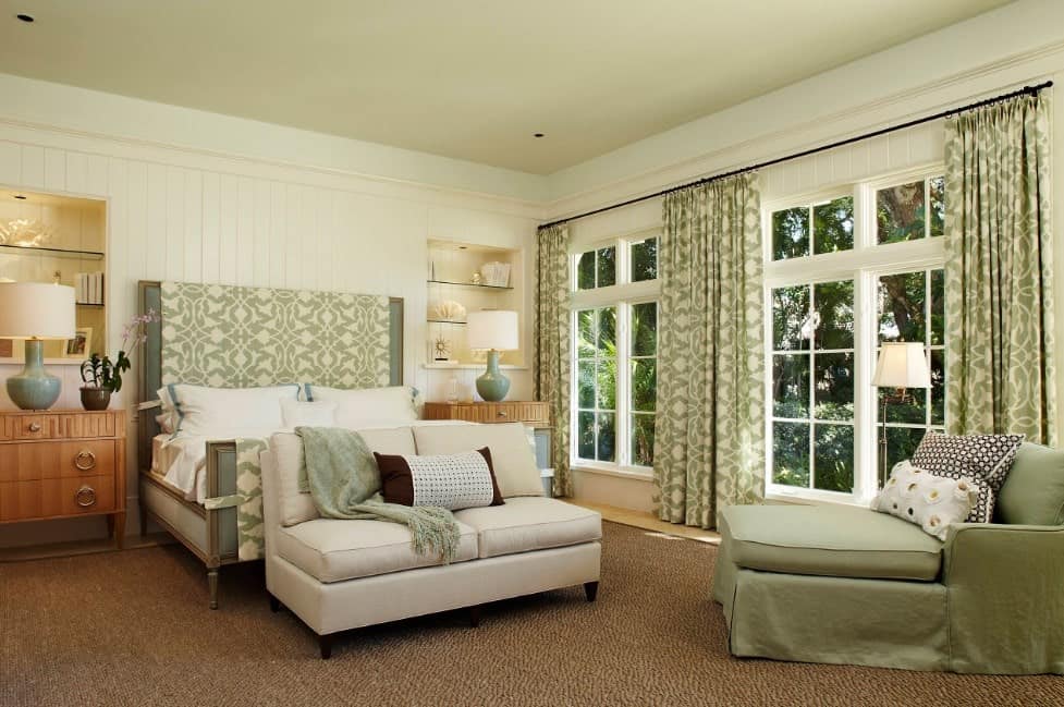 主卧室以绿色和地毯地板为特色。这张床和座椅在一起看起来很舒服。