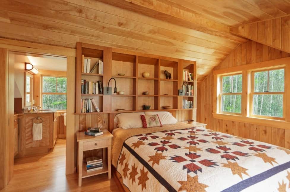 质朴的主卧室被木墙、天花板和地板包围。床架和内置的架子，以及边桌都是木制的。
