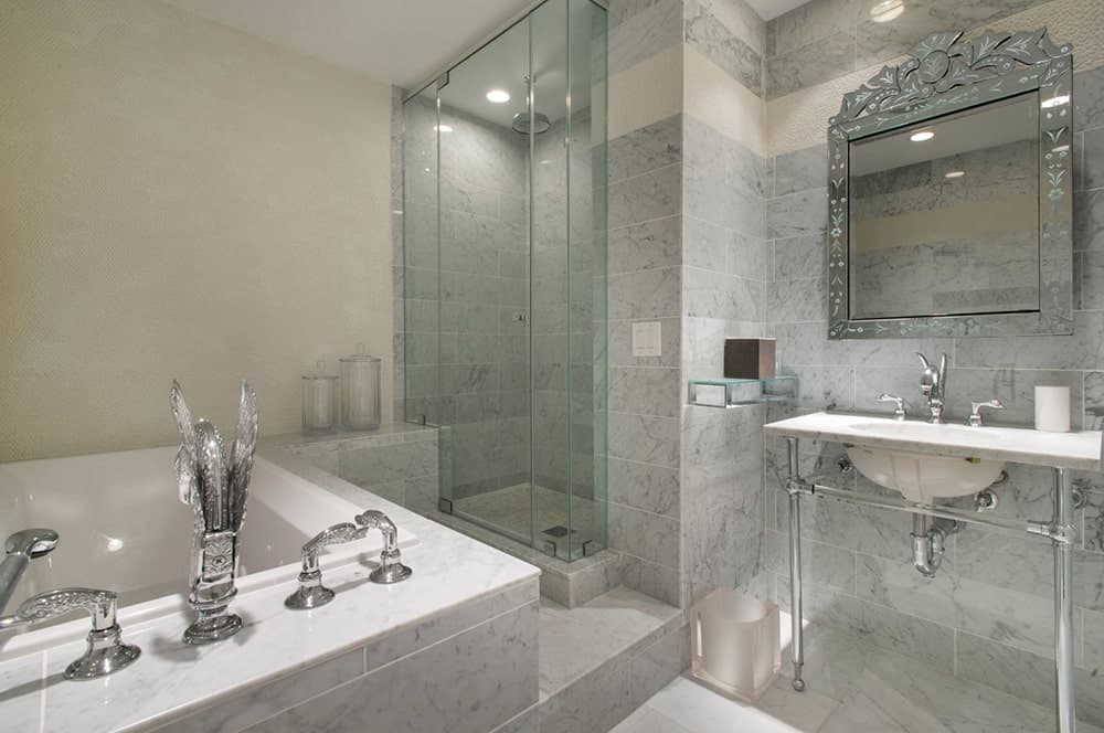 当代浴室设有一个带豪华设备的浴缸，旁边是步入式淋浴，浴室水槽配有一面声明镜。