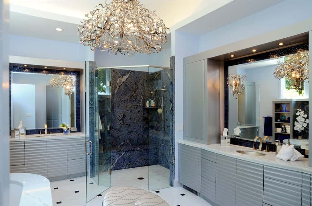 当代浴室强调独特的吊灯和壁灯补充深蓝色瓷砖墙的步入式淋浴。