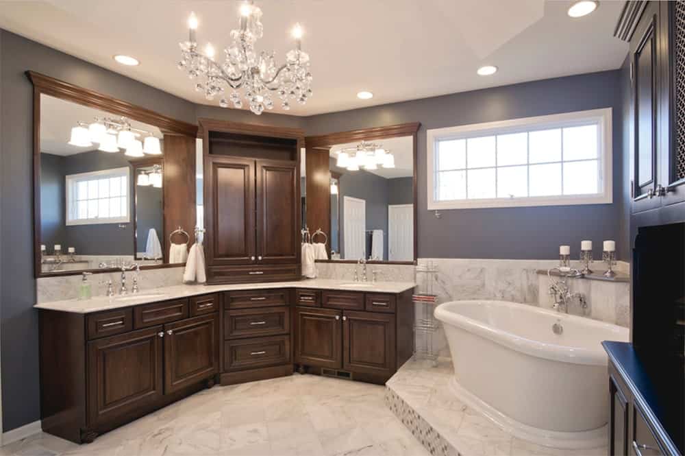 传统的浴室设有一个弯曲的双洗手台，配有木制橱柜和白色大理石台面，与较低的墙壁和地板相匹配。它由壁式烛台和一盏别致的枝形吊灯照明。