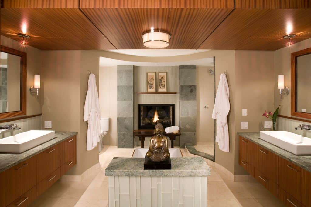 古董青铜佛像提供了一个独特的和诱人的焦点随着现代壁炉在这个复杂的对称浴室。