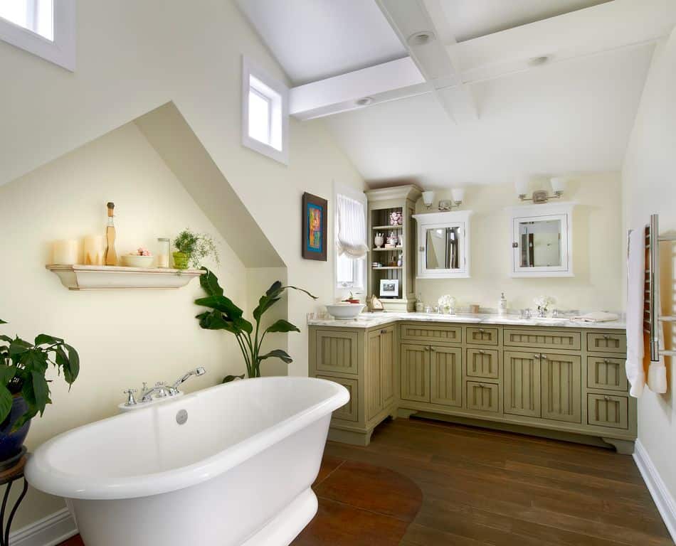 中等大小的浴室设有一个l形的梳妆台，上面铺着灰色大理石，并由木橱柜和硬木地板上的独立浴缸完成。