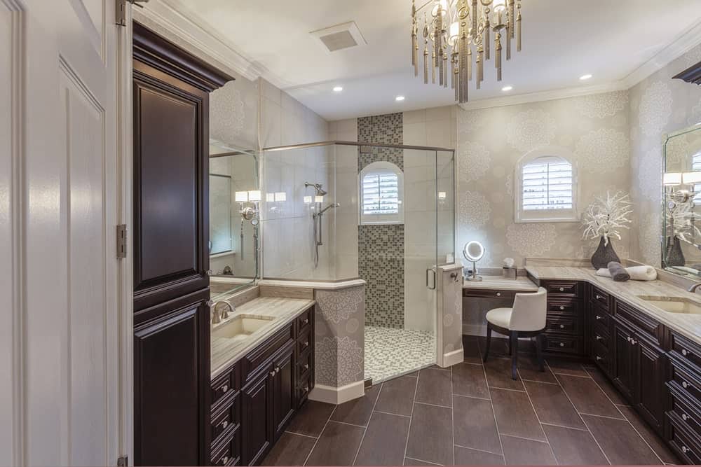在这个别致的浴室里，一间以马赛克瓷砖为特色的步入式淋浴间被深色木洗手台和灰色大理石台面包围。它的特点是一个可爱的吊灯挂在硬木地板上。