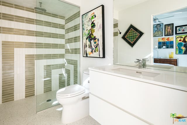 这间主浴室提供了围绕淋浴区的时尚瓷砖墙。白色的洗涤台闪闪发光。