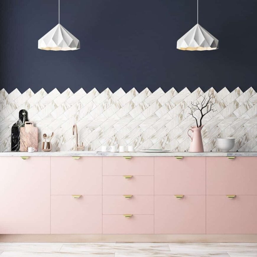 这个厨房拥有一个引人注目的后挡板，由可爱的吊灯照亮。它包括一个浅粉色的橱柜，与深蓝色的墙壁形成对比。