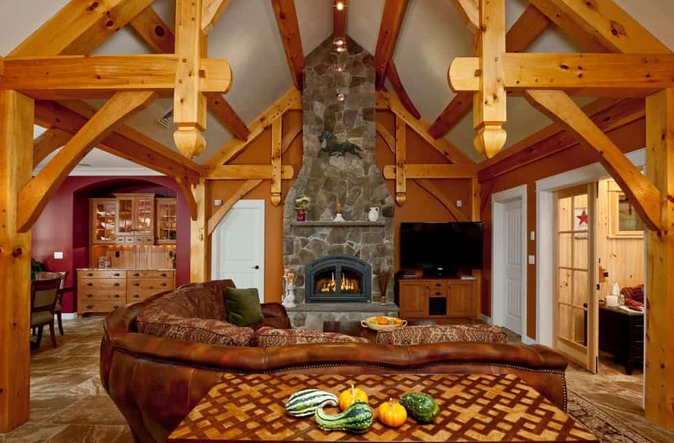 工匠风格的客厅，可见木梁，棕色l形皮革沙发，壁炉和质朴的木橱柜。