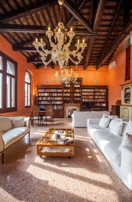 结合了维多利亚式和乡村风格的客厅，有一个图书馆，维多利亚式的枝形吊灯，长方形的中央桌子，白色的长沙发，和瓷砖地板。