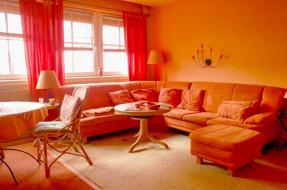 客厅里的沙发、枕头、中间的圆桌、窗帘和墙壁都散发着橙色的气息。