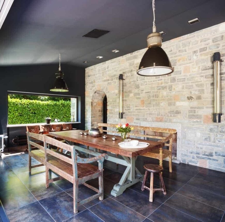 餐厅里有一张质朴的餐桌和椅子，铺着瓷砖地板，黑色的墙壁和天花板，旁边还有一个壁炉。