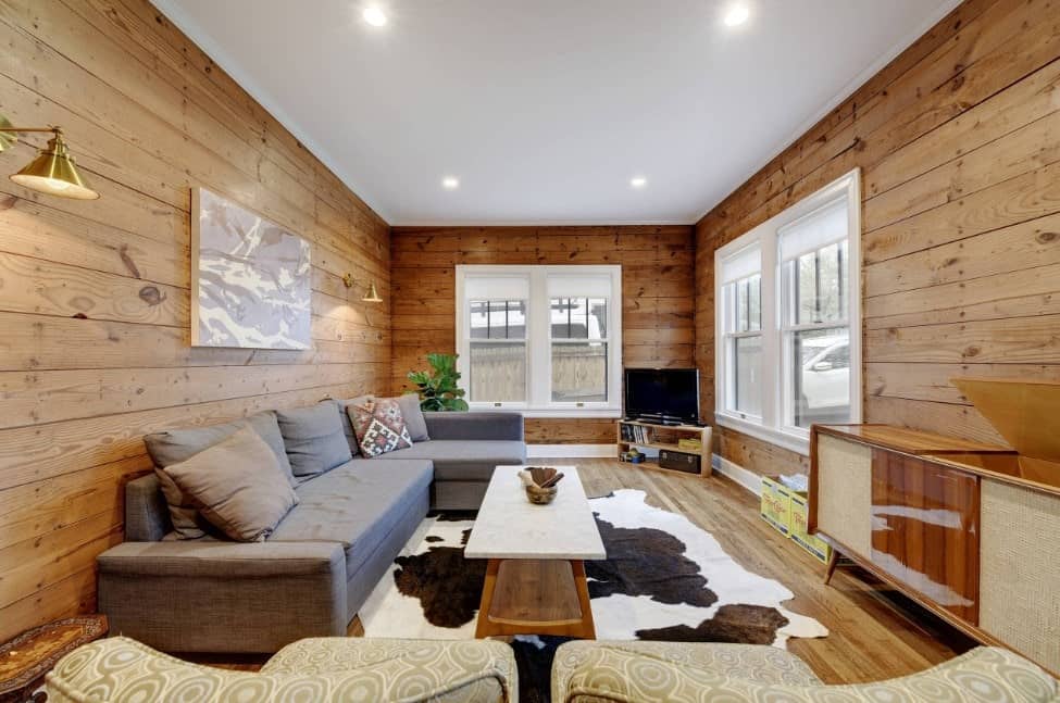 宽敞的正式客厅，配有舒适的沙发和时尚的地毯，覆盖着与木墙相匹配的硬木地板。