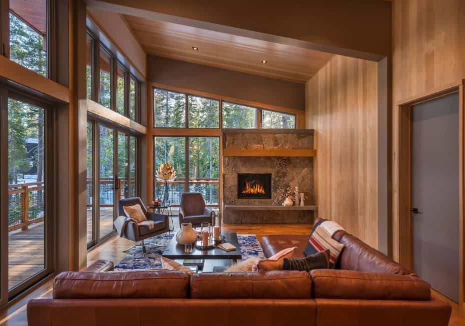 客厅配有棕色皮沙发和一对时尚的椅子，椅子放在覆盖硬木地板的时尚地毯上。