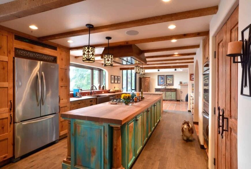 绿色心疼早餐岛与宽木板木板顶部增加了质朴的基调在这个厨房。它有别致的吊灯，还有木制橱柜和硬木地板。