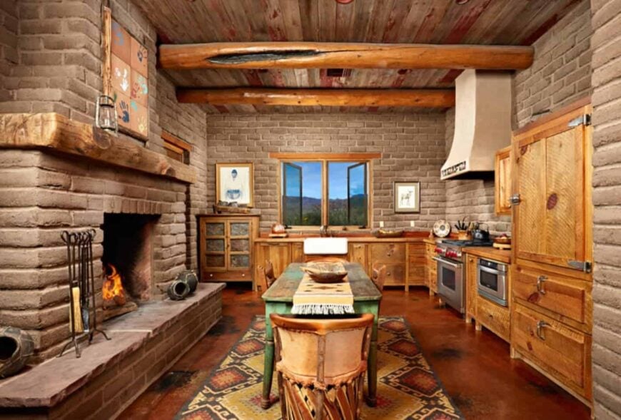 混凝土砖墙和木制橱柜围绕着这个厨房。房间里有一座壁炉，正对着一张绿色的桌子，桌子放在黄色的地毯上。