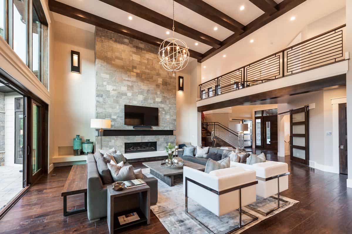 宽敞的客厅，现代座椅，天然木桌，一个大的石头壁炉，和一个球形吊灯挂在横梁天花板上。