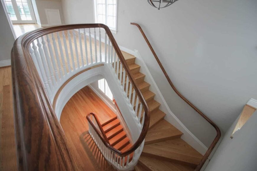 从木楼梯的角度看，白色的推力杆与灰色的墙壁和硬木地板相匹配。