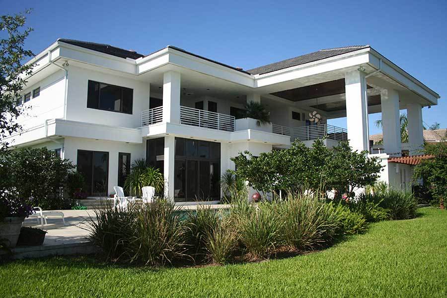 这座当代住宅有着鲜明的白色外墙，郁郁葱葱的绿色草坪和植物使其更加突出。