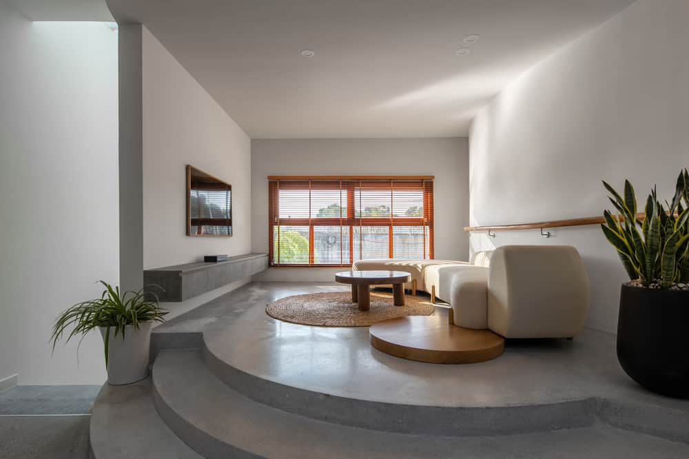 极简主义的当代客厅利用自然光和一些元素来做出戏剧性的陈述。高架入口增添了独特的触感。