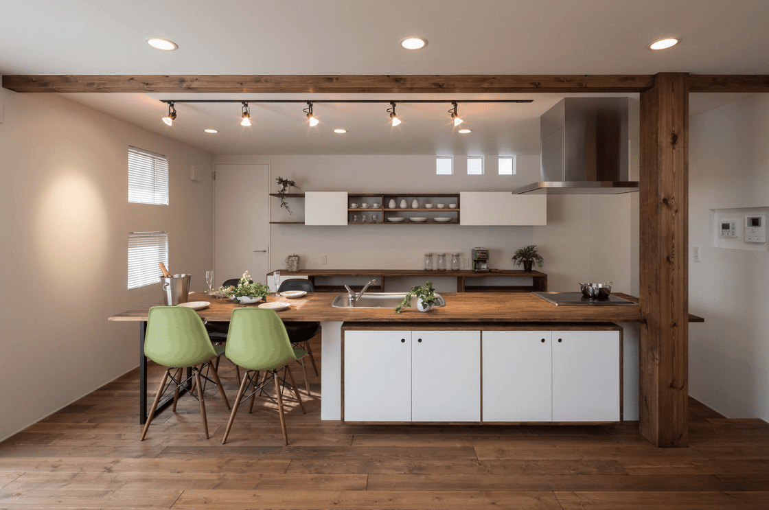 新鲜的厨房由木梁构成，与木板地板和柜台相辅相成。它有一个白色的半岛，搭配黑色和浅绿色的凳子。
