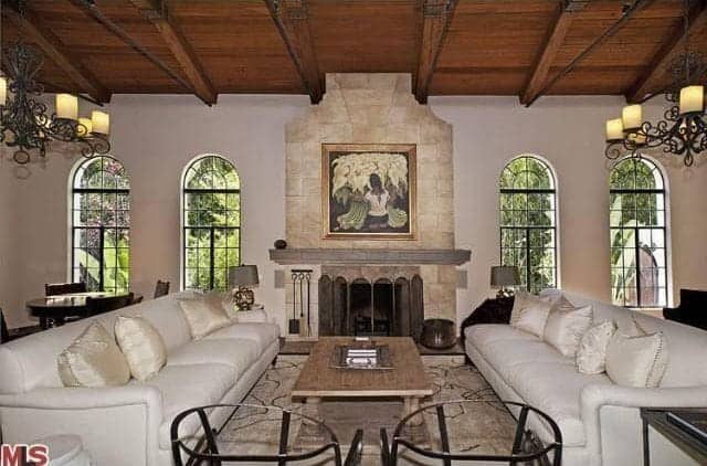 对称设计的经典客厅。它包括白色沙发和一对配套的扶手椅，由木梁天花板上悬挂的老式枝形吊灯照明。