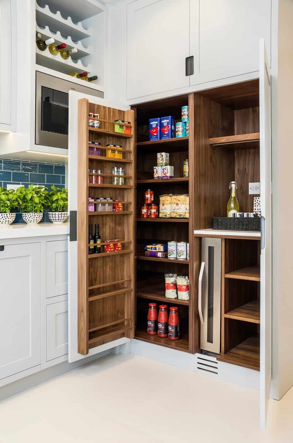 光滑的厨房设有一个秋千式食品储藏室，内部有天然木材和白色橱柜，以及安装在烤箱架上的内置酒架。