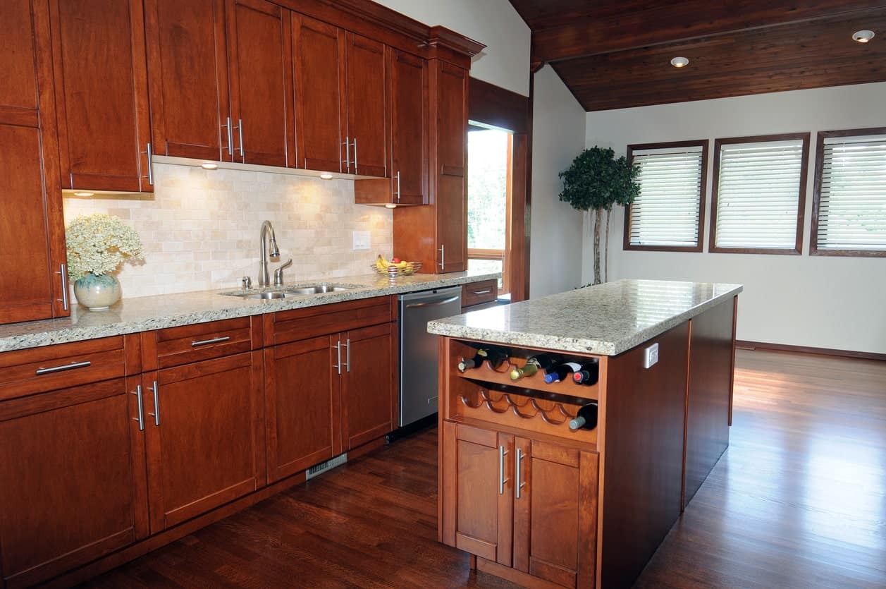 厨房与木质橱柜和大理石台面补充早餐岛。它有一个安装在内置橱柜上方的酒架。