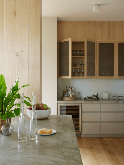 舒适的厨房提供磨砂玻璃前葡萄酒杯架安装在木面板和嵌入式葡萄酒冰箱旁边的白色橱柜。