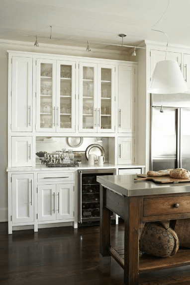 厨房有白色橱柜和玻璃前架，以及一个内置的葡萄酒冷却器，放在深色硬木地板上。