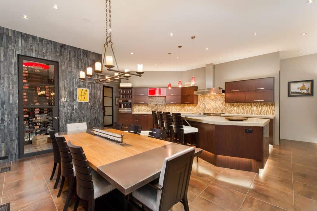 豪华的餐厅厨房设有一面灰色的强调墙，配有面向木制餐厅的玻璃前葡萄酒冰箱。